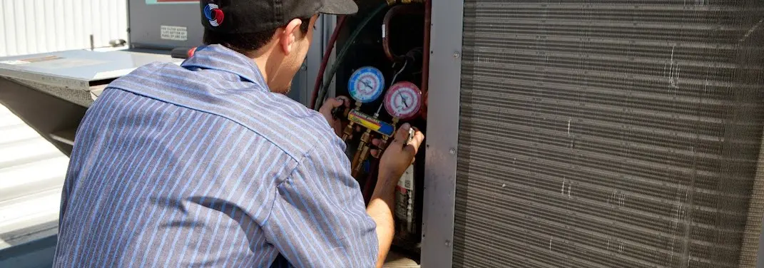 HVAC technician servicing a condenser unit in Watchung